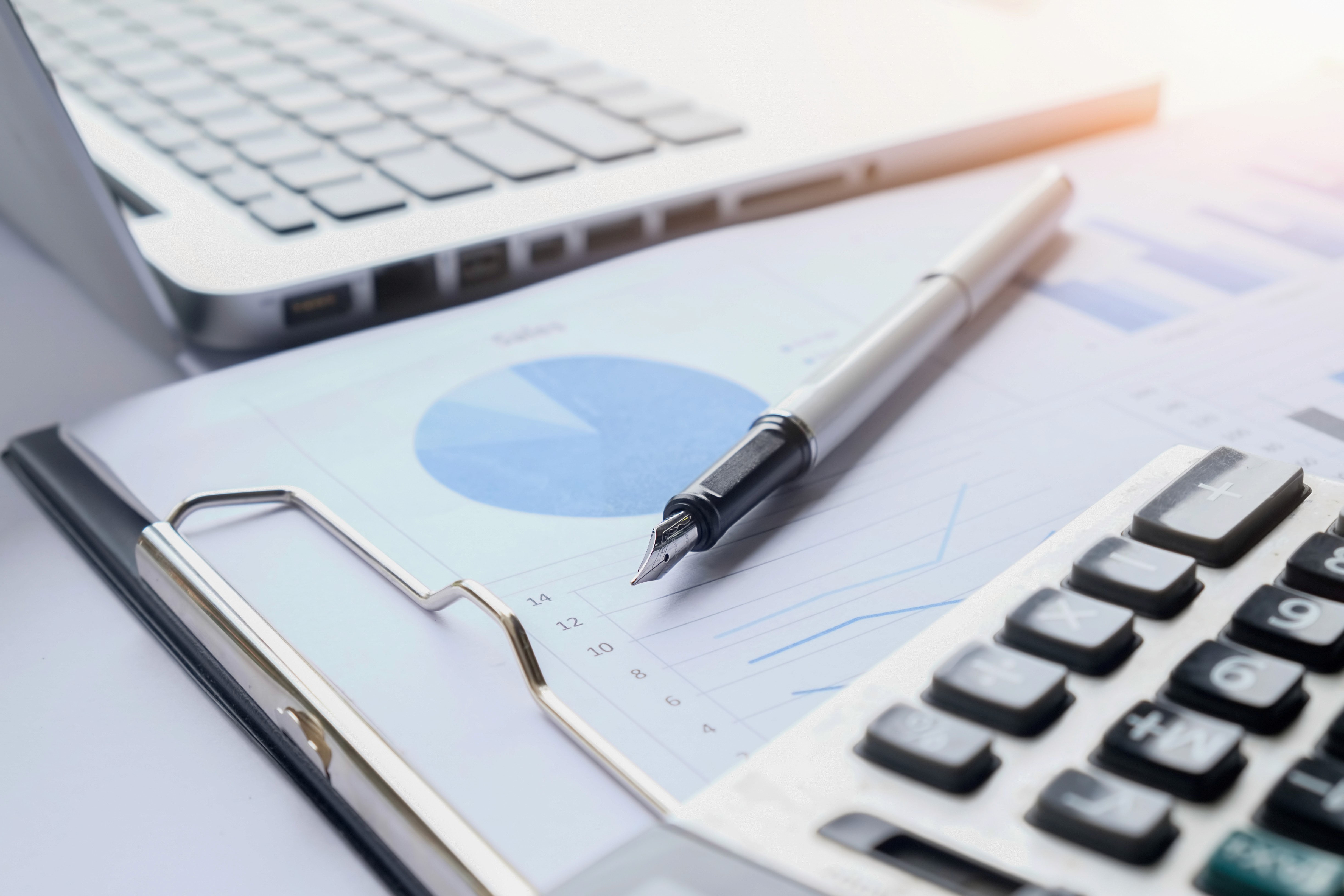 Workspace contábil com laptop, calculadora e relatórios financeiros